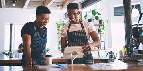 Two men smiling looking at a tablet screen