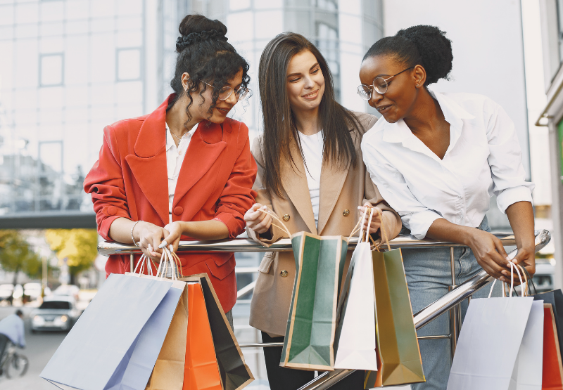 Group of shoppers carrying colourful retail bags outside a shopping centre