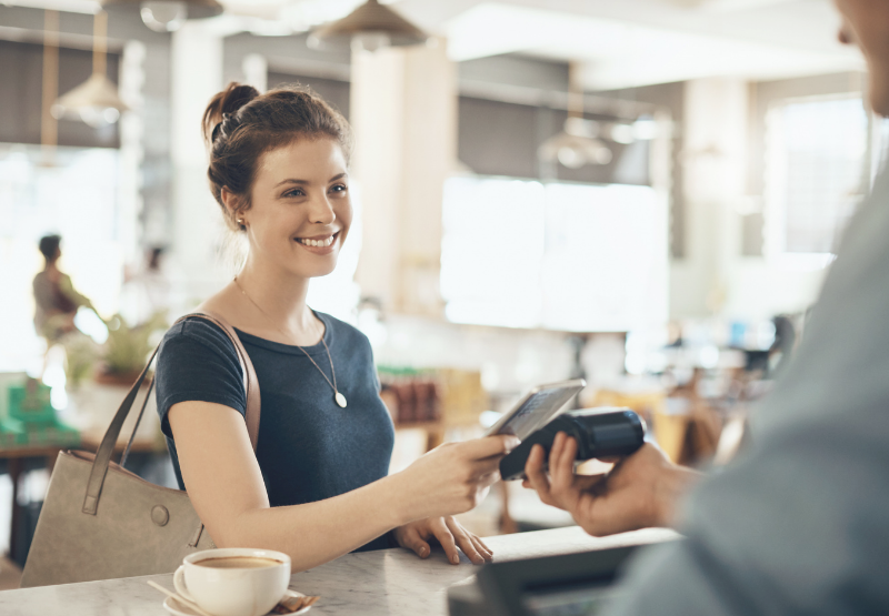 Client utilisant un terminal de débit à la caisse d’une petite entreprise.
