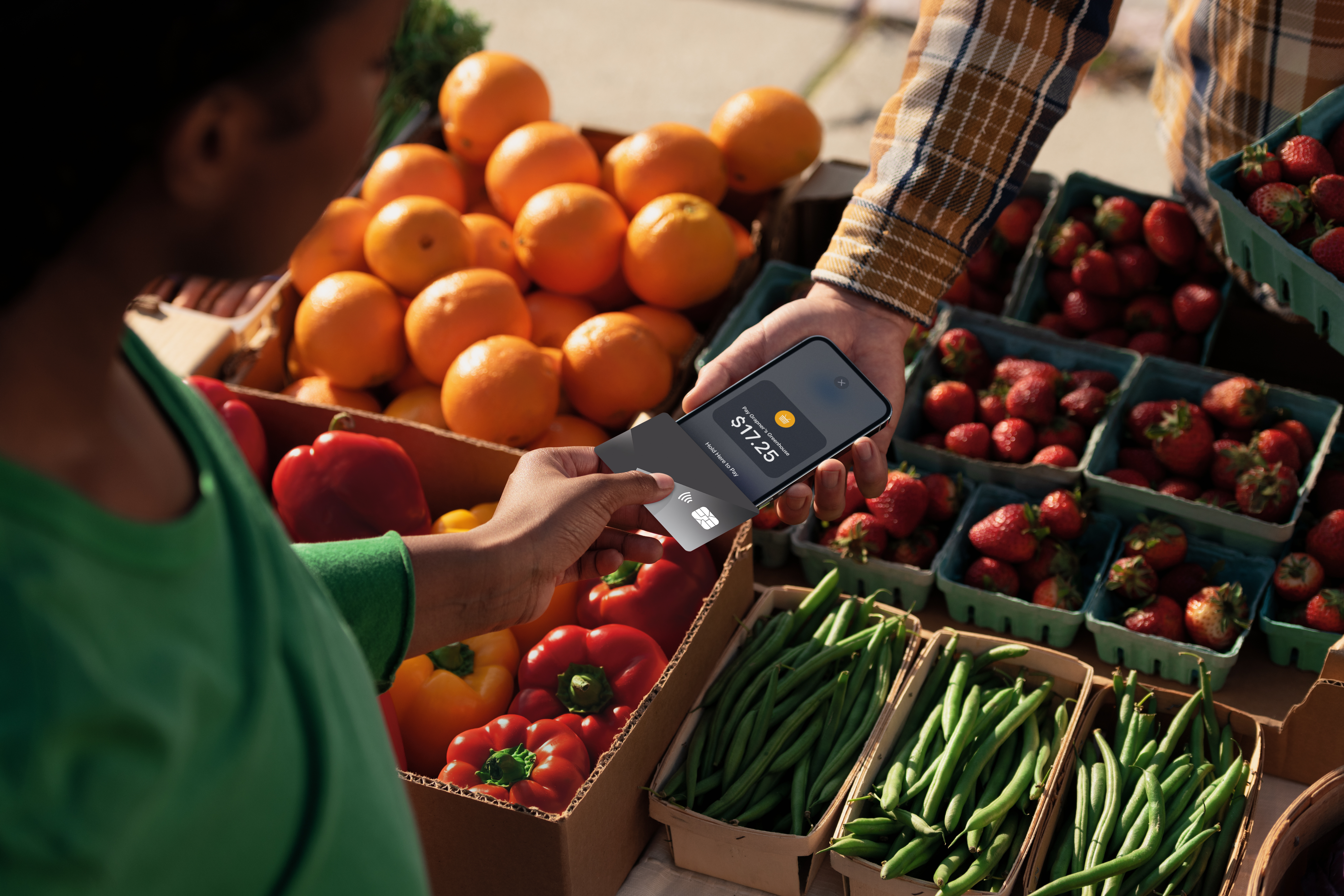 Customer taps a smartphone on a handheld payment terminal while a cashier holds the device at a café checkout.
