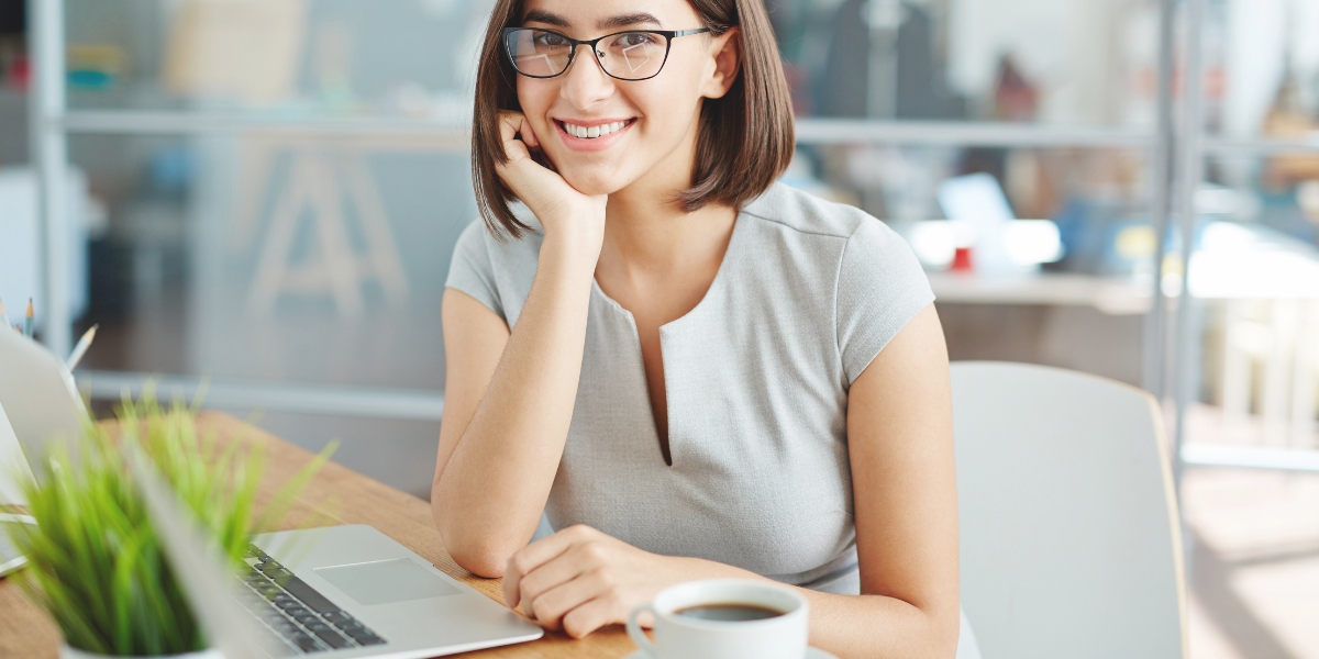 Person working at a laptop in a modern office with a coffee cup on the desk