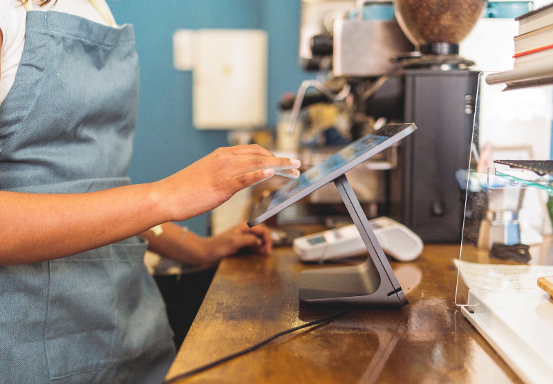 Small business employee using a touchscreen POS system at a café counter