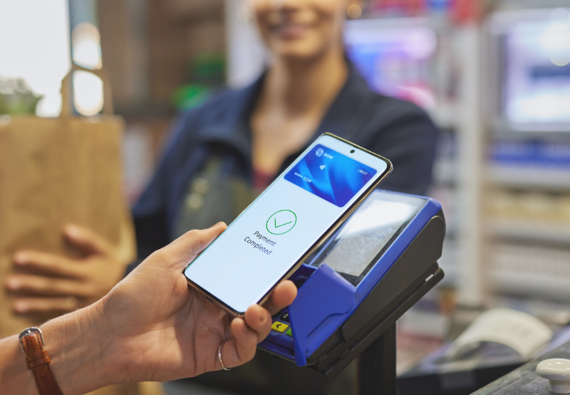 Customer making a contactless mobile payment at a checkout terminal in a small business.