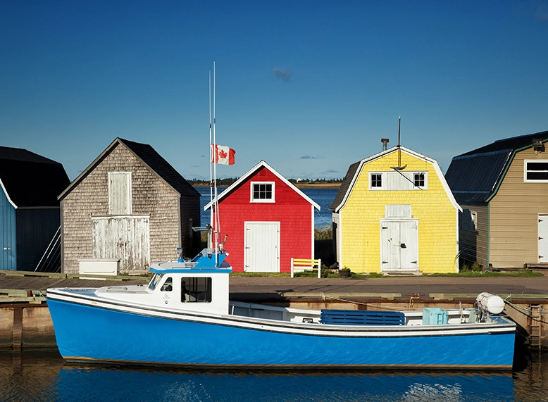 Des maisons de l’Île-du-Prince-Édouard derrière un bateau. 