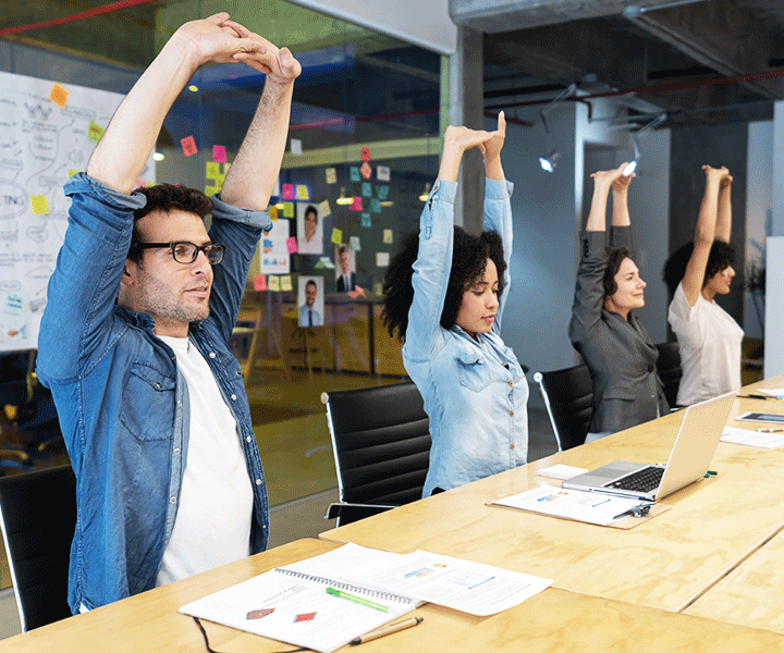 Employees stretching at a boardroom meeting