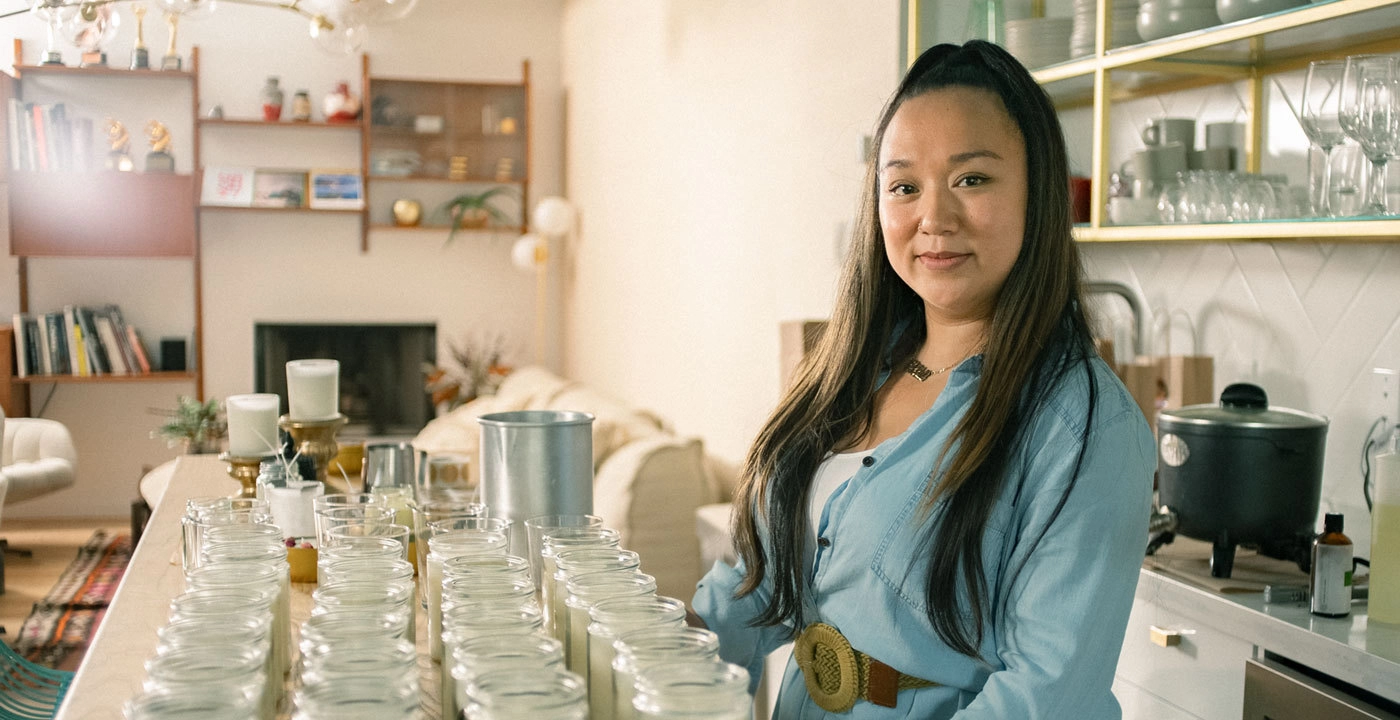 Ella Flores of Ellament Candles in her store with a large selection of candles in front of her.