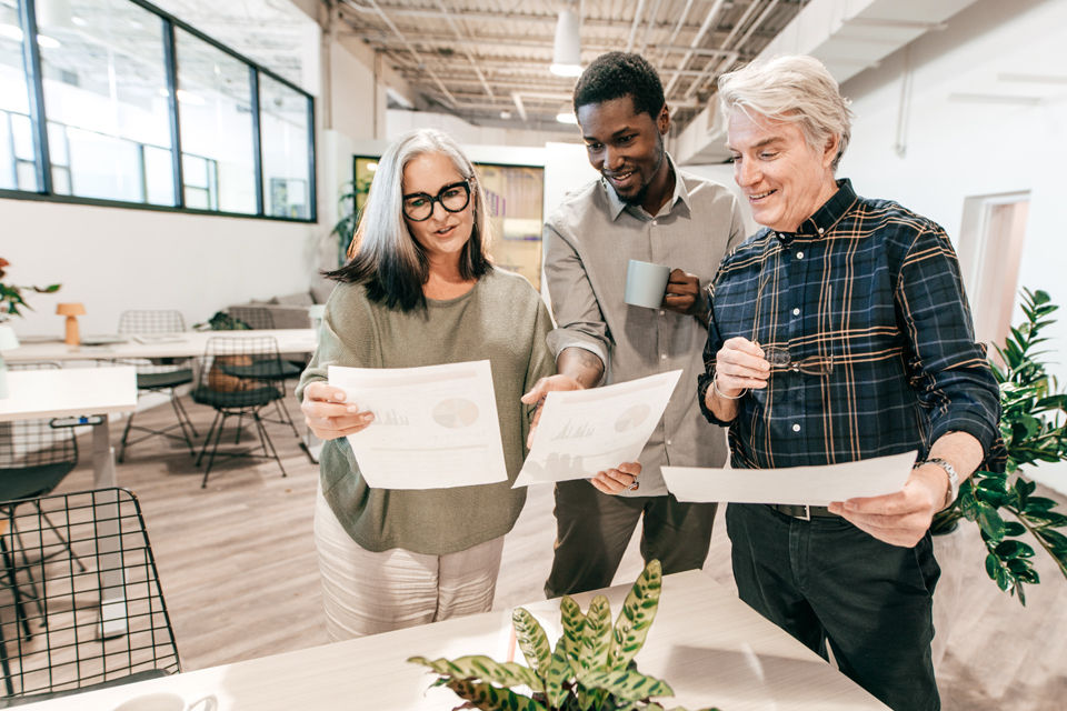 Three business people look at documents in a fancy engineering office.