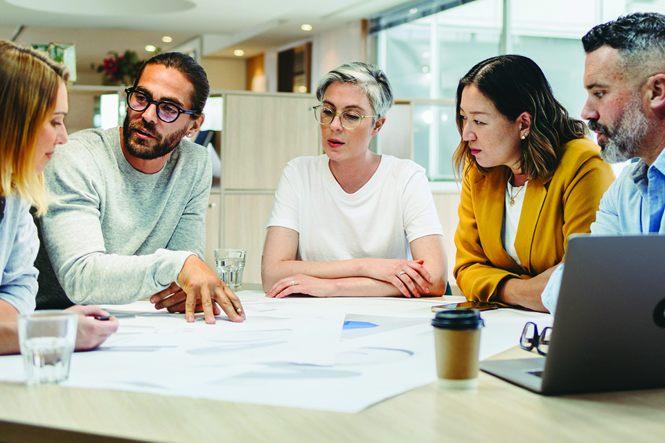 Business people sitting on a boardroom table with coffee