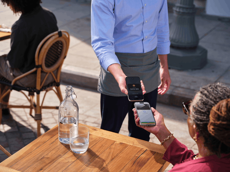 Customer completing a secure mobile payment using a smartphone during a restaurant purchase.