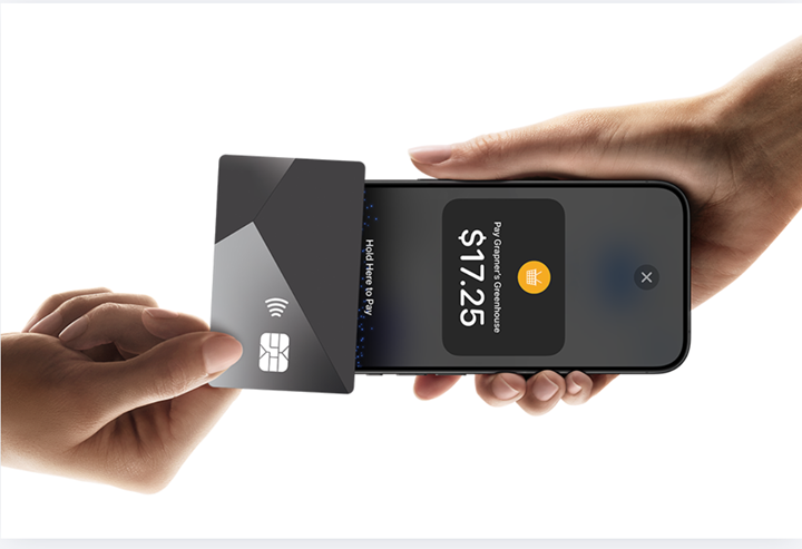 A customer holds a contactless payment card against an iPhone displaying a Tap to Pay transaction screen, illustrating mobile payment acceptance without a card reader.