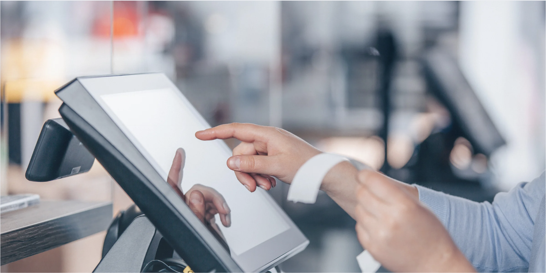 A customer using a touchscreen self-checkout terminal in a retail setting.